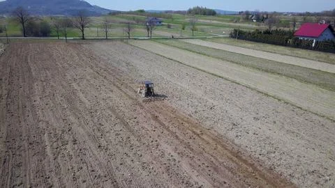 A farmer on a tractor with a seeder sows grain in plowed land in a private fi Stock Photos