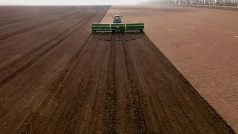 Farmer with tractor seeding - sowing crops at agricultural fields in spring Stock Footage 236949493