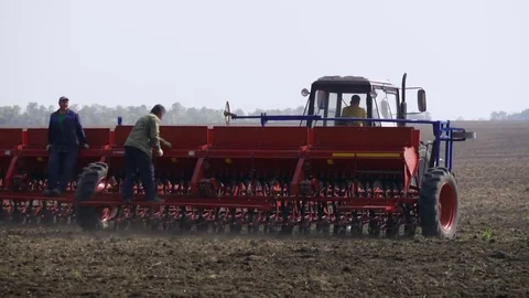 Farmer with tractor sowing on agricultural fields on sunny spring day Stock Footage 73879186