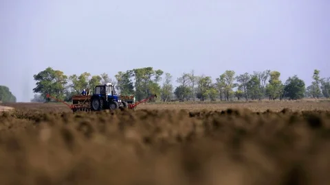 Farmer with tractor sowing on agricultural fields on sunny spring day Stock Footage 73879248