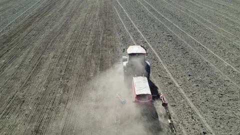 Farmer in a tractor with a sowing unit sowing farmland Stockbeeldmateriaal 235976287