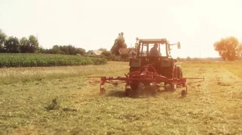 Farmer on a tractor tedding the grass Stock Footage 10586444