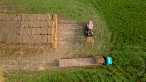 Farmer unload round bales of straw from Hay Trailer with a front end loader. Video stock 161420067
