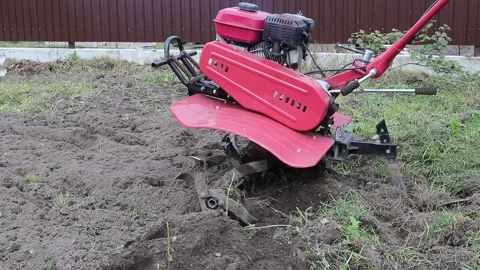 A farmer uses a red-colored technique to cultivate a small plot of land. plows,  Vídeos de archivo 253630856