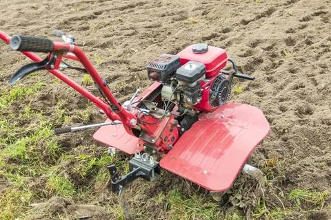 A farmer uses a red-colored technique to cultivate a small plot of land. plow Stock Photos