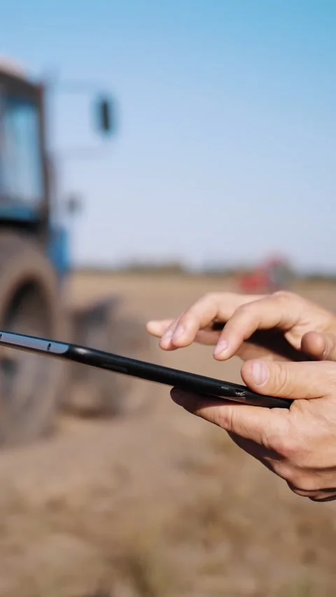 Farmer is using digital tablet. close-up. on farm field, near tractor, on farm Stock Footage 307838339