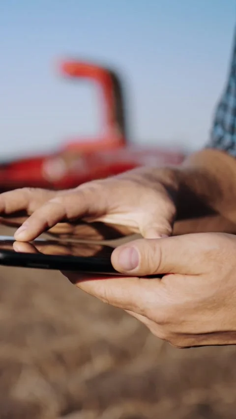 Farmer using digital tablet. close-up. on farm field, on farm machinery backdrop Stock Footage 311989463