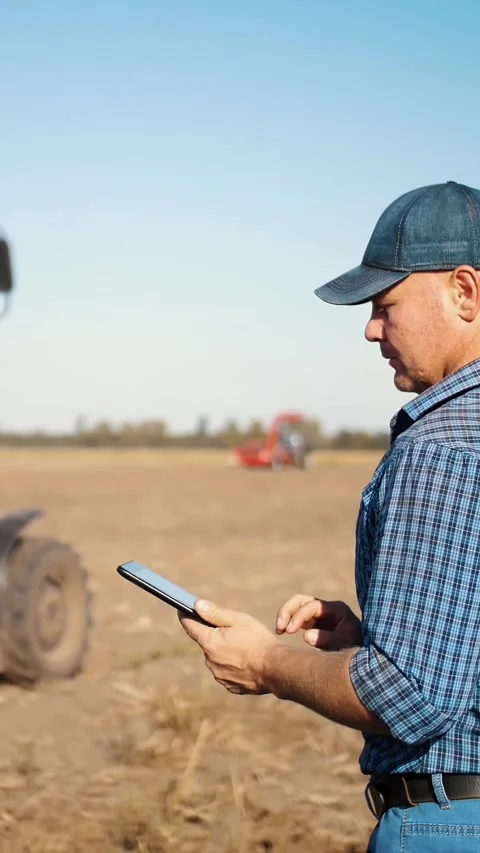 Farmer is using digital tablet. on farm field, near tractor, on farm machinery Stock Footage 314434754