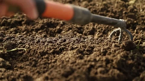 Farmer using a hand hoe  loosening fertile soil for planting Stock Footage 332488207