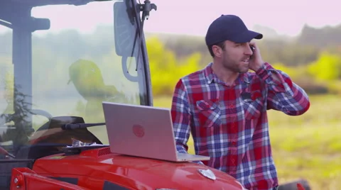 Farmer using laptop computer and cell phone Stockbeeldmateriaal 55528690