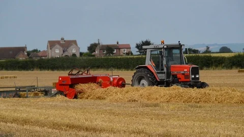 Farmer using straw baling machine at harvest united kingdom Stock Footage 77404054