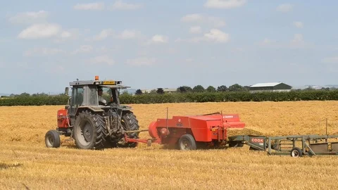 Farmer using straw baling machine at harvest united kingdom Stock Footage 77405902
