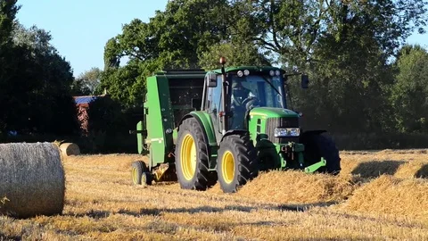 Farmer using straw baling machine at harvest time ellerton yorkshire uk Stock Footage 78907673