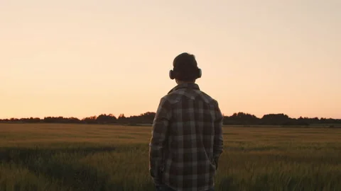 Farmer in virtual reality helmet in front of a sunset agricultural landscape Stock Footage 218606963