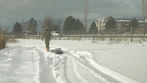 Farmer walking in snow with a sled Stock Footage 100400068