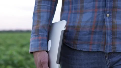 A farmer walks with a digital tablet through an agricultural field. Stock Footage 269143382