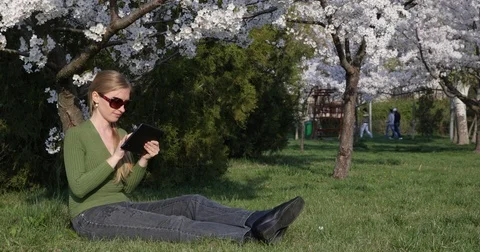 Farmer Woman Analyzing Data On Digital Tablet Sitting Green Grass Spring Flower Video stock 72762530