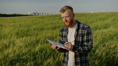 A farmer writes down crop data in a notebook while standing in a field Stock Footage 234265180