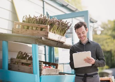 Farmerís market worker with clipboard checking inventory next to asparagus Stock Photos