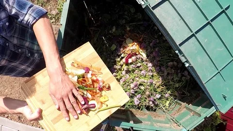Farmer's hands throwing out kitchen waste to the garden compost heap Stock Footage