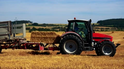 Farmers harvest grain from the field (farmer loads haystacks on the tractor) Stock Footage