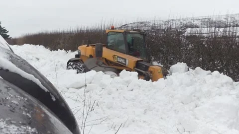 A farmer's JCB telehandler makes easy work of clearing deep snowdrifts Stock Footage 148733754