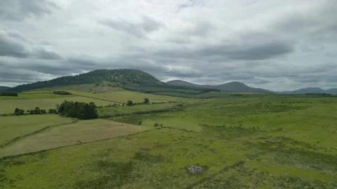 Farmland patchwork fields flying towards distant hill Great Mell Fell on 動画素材 247975495