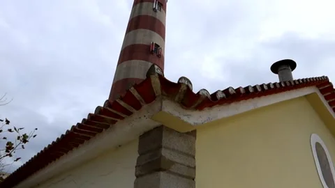 Faro da Barra emerging behind a rooftop adorned with red tiles in Praia da Stock Footage 251727687