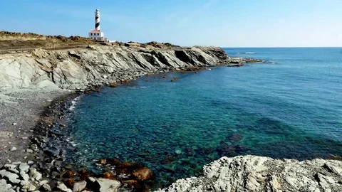 Faro de Favaritx lighthouse with tor and rocky beach, Menorca, Minorca Stock Footage 73107583