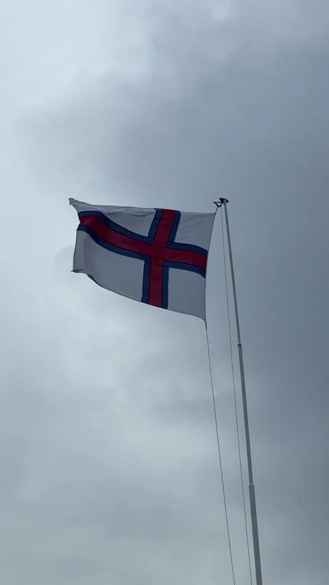 The Faroe Islands flag waving in the wind under a cloudy sky Stock Footage 312975825