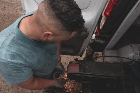 Farrier at work: Young blacksmith smoothing a horseshoe for perfect fit. Stock Photos