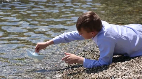 Fascinated boy prepares and puts to sea toy paper ship Video stock 49922354