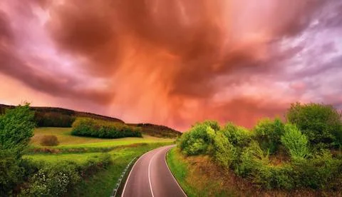 Fascinating rain clouds over a road at sunset Stock Photos