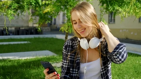 Fascinating smiling young lady in stylish clothes using her smartphone sitting o Stock Footage 112352731