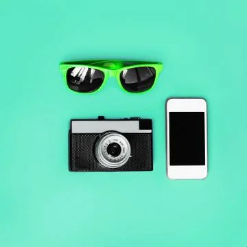Fashion accessory. Sunglasses, vintage camera and smartphone on green backgro Stock Photos