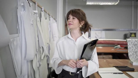 Fashion designer making notes while looking at patterns in sewing studio 스톡 동영상 107419963
