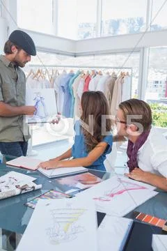 Fashion designer showing a draw to his colleague Stock-Fotos