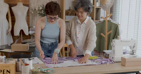 Fashion Designer Teaching Apprentice To Cut Fabric Patterns In Sewing Works.. Stock Footage 336248245