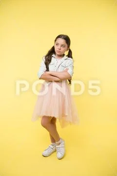Fashion model agency for kids. Child keep arms crossed on yellow background Stock Photos