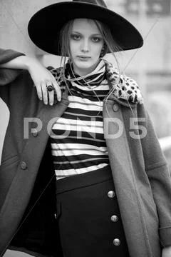 Fashion Model In Coat And Hat Poses Outdoors