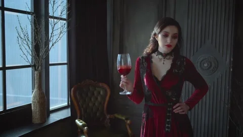 Fashion model posing in dark studio. Woman holding glass blood wine. Red dress Stock Footage 155997664