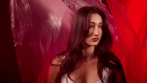 Fashion model posing in red light with plastic fabric, beauty and art concept, Stock Footage 337004024