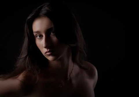Fashion model posing in studio with dramatic lighting on black background Stock Photos
