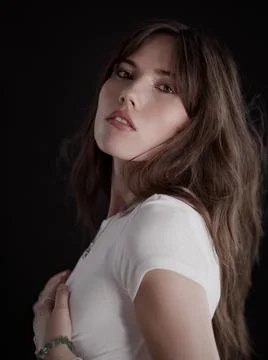 Fashion model posing in studio with hand on chest and dark background Stock Photos