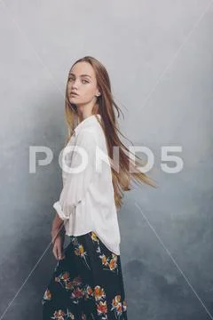 Fashion teenager girl standing against blue textured grunge wall background. Stock Photos