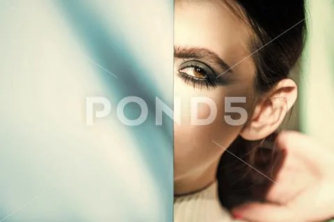 Fashion woman model posing. Woman or girl hide half face makeup at blue wall Stock Photos