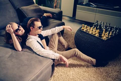 Fashionable couple in elegant clothes and sunglasses relaxing in a luxury apa Stock Photos