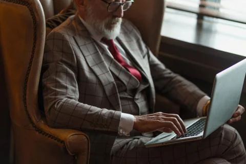 Fashionable elderly male writer wearing elegant clothes working on laptop. Stock Photos