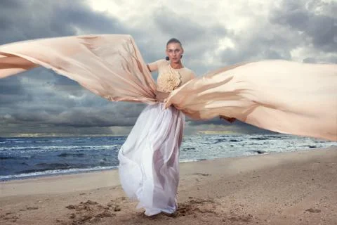 Fashionable model posing in extremely long dress on the seashore Foto stock