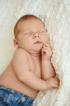 Fashionable newborn baby in jeans sleeping in bed. Fashion for children. Stock Photos